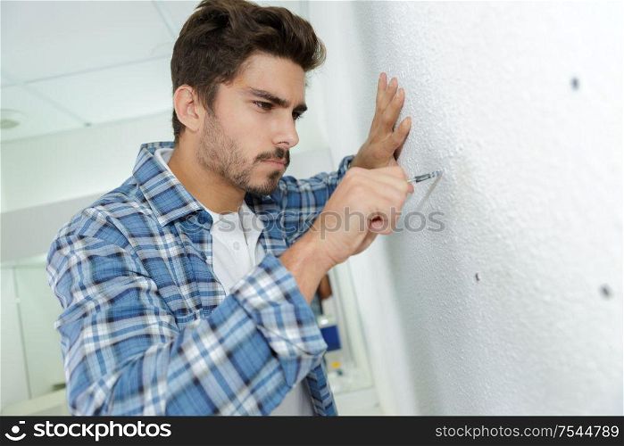skilled electrician preparing holes before installing appliance
