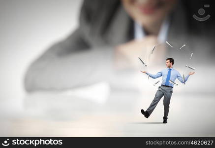 Skillful businessman. Businesswoman looking at miniature of man juggling with items