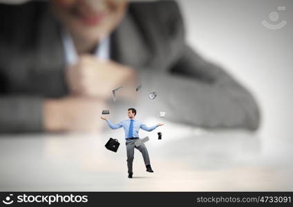 Skillful businessman. Businesswoman looking at miniature of man juggling with items