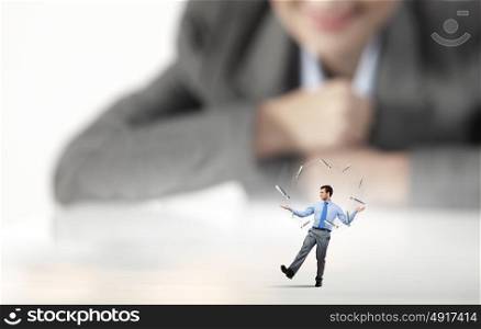 Skillful businessman. Businesswoman looking at miniature of man juggling with items