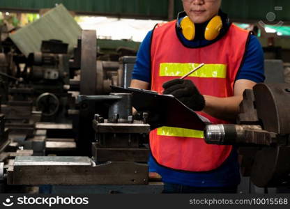 Skillful factory worker working with clipboard to do job procedure checklist . Factory production line occupation quality control concept .. Skillful factory worker working with clipboard to do job procedure checklist .