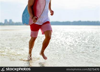 skimboarding, water sport and people concept - happy smiling young man with skimboard on summer beach. happy young man with skimboard on summer beach