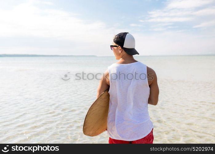 skimboarding, water sport and people concept - happy young man with skimboard on summer beach. happy young man with skimboard on summer beach