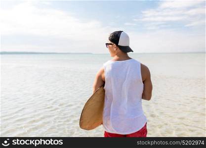 skimboarding, water sport and people concept - happy young man with skimboard on summer beach. happy young man with skimboard on summer beach
