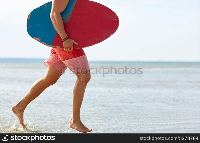 skimboarding, water sport and people concept - young man with skimboard on summer beach. young man with skimboard on summer beach