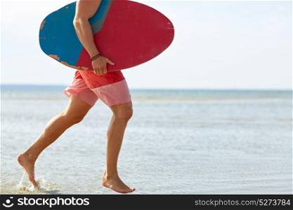 skimboarding, water sport and people concept - young man with skimboard on summer beach. young man with skimboard on summer beach