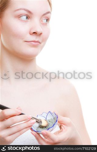 Skin care, cosmetology concept. Woman mixing mud face mask with brush in little porcelain bowl, isolated. Woman mixing face mask in little porcelain bowl
