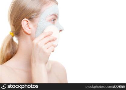 Skin care, cosmetology concept. Woman removing mud algae mask from face with cosmetic sponge.. Woman having mud green mask on her face