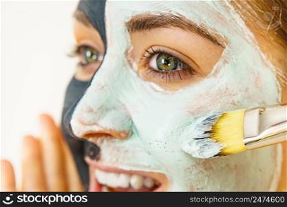 Skin care. Female applying green purifying mud mask, cosmetic healing clay to face, using brush. Beauty and wellness. Spa and acne treatment.. Female applying green mud facial mask