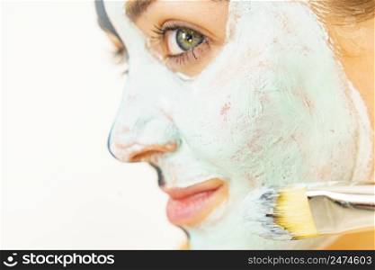 Skin care. Female applying green purifying mud mask, cosmetic healing clay to face, using brush. Beauty and wellness. Spa and acne treatment.. Female applying green mud facial mask