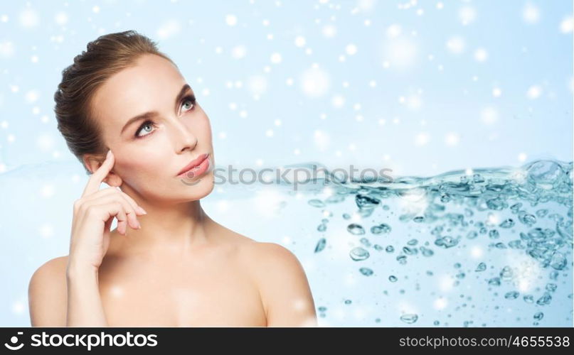 skin care, people, moisturizing and beauty concept - beautiful young woman face over water splash bubbles on blue background and snow