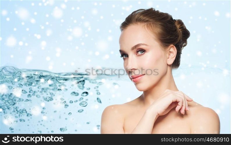 skin care, people, moisturizing and beauty concept - beautiful young woman face over water splash bubbles on blue background and snow