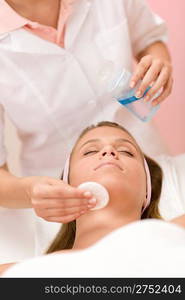 Skin care - woman cleaning face by beautician