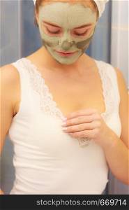 Skin care. Woman in bathroom with green clay mud mask on face. Girl taking care of oily complexion. Beauty treatment.. Woman face with green clay mud mask