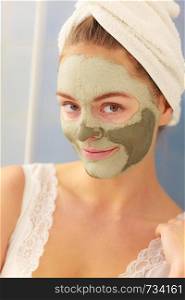 Skin care. Woman in bathroom with green clay mud mask on face. Girl taking care of oily complexion. Beauty treatment.. Woman face with green clay mud mask