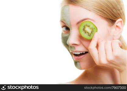 Skin care. Woman in clay mud mask on face covering eye with slice of kiwi. Girl taking care of dry complexion. Beauty treatment.