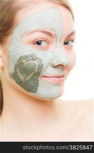 Skin care. Woman in clay mud mask with heart symbol of love on cheek isolated on white. Girl taking care of dry complexion. Beauty treatment.