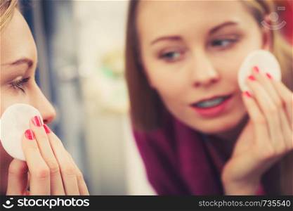 Skin complexion care concept. Young woman using cotton pad to remove make up or dirt from face.. Woman using cotton pad to remove make up