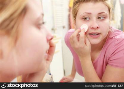 Skin complexion care concept. Young woman using cotton pad to remove make up or dirt from face.. Woman using cotton pad to remove make up