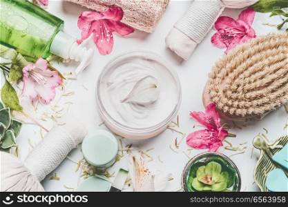 Skin cream with flowers petals and others body care cosmetic products and accessories on white background, top view