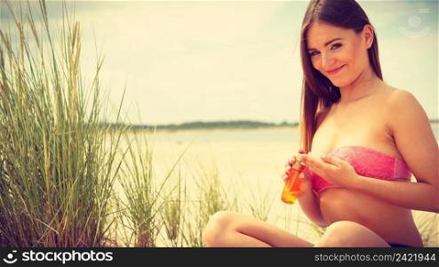 Skin protection in summer. Woman on beach using sun oil. Young beauty girl taking sunbath on sunny day. Holidays time.. Woman with sun oil.