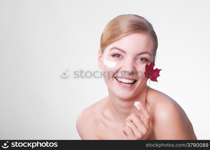 Skincare habits. Face of young woman with leaf as symbol of red capillary skin on gray. Girl taking care of her dry complexion applying moisturizing cream. Beauty treatment.