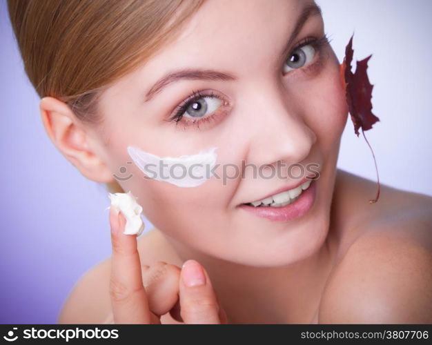 Skincare habits. Face of young woman with leaf as symbol of red capillary skin on gray. Girl taking care of her dry complexion applying moisturizing cream. Beauty treatment.