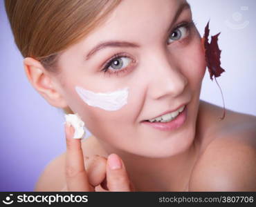 Skincare habits. Face of young woman with leaf as symbol of red capillary skin on gray. Girl taking care of her dry complexion applying moisturizing cream. Beauty treatment.