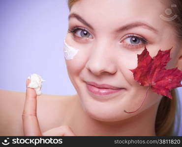 Skincare habits. Face of young woman with leaf as symbol of red capillary skin on gray. Girl taking care of her dry complexion applying moisturizing cream. Beauty treatment.