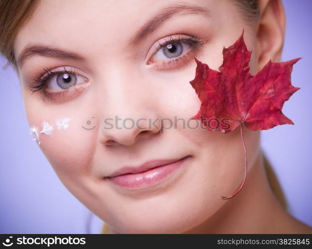 Skincare habits. Face of young woman with leaf as symbol of red capillary skin on gray. Girl taking care of her dry complexion applying moisturizing cream. Beauty treatment.