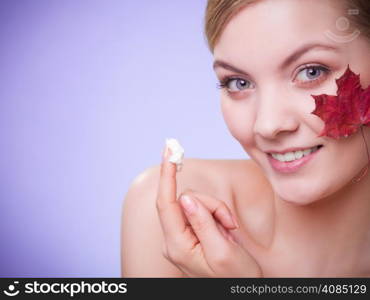 Skincare habits. Face of young woman with leaf as symbol of red capillary skin on gray. Girl taking care of her dry complexion applying moisturizing cream. Beauty treatment.