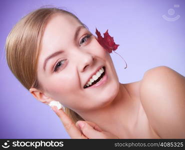 Skincare habits. Face of young woman with leaf as symbol of red capillary skin on gray. Girl taking care of her dry complexion applying moisturizing cream. Beauty treatment.