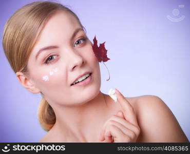 Skincare habits. Face of young woman with leaf as symbol of red capillary skin on gray. Girl taking care of her dry complexion applying moisturizing cream. Beauty treatment.