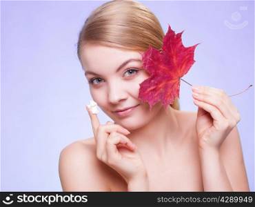 Skincare habits. Face of young woman with leaf as symbol of red capillary skin on violet. Girl taking care of her dry complexion applying moisturizing cream. Beauty treatment.