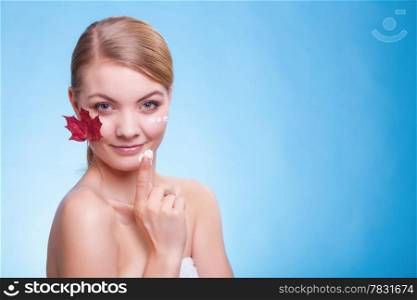 Skincare habits. Face of young woman with leaf as symbol of red capillary skin on blue. Girl taking care of her dry complexion applying moisturizing cream. Beauty treatment.