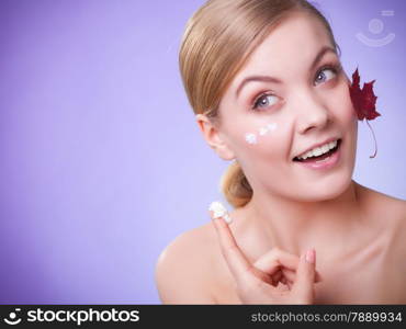 Skincare habits. Face of young woman with leaf as symbol of red capillary skin on gray. Girl taking care of her dry complexion applying moisturizing cream. Beauty treatment.