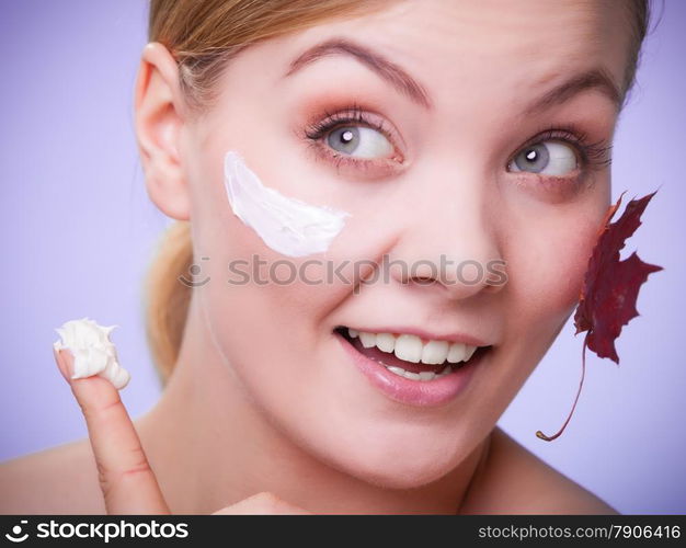 Skincare habits. Face of young woman with leaf as symbol of red capillary skin on gray. Girl taking care of her dry complexion applying moisturizing cream. Beauty treatment.