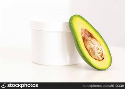 Skincare with natural cosmetics. White cosmetic jar of cream with half of the avocado near against white background, copy space, mockup. Skincare with natural cosmetics. White cosmetic jar of cream with half of the avocado near against white background, copy space, mockup.