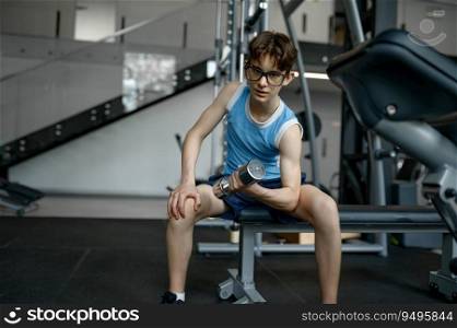 Skinny nerd boy doing lifting workout with dumbbells training at gym. Sport, strength and active lifestyle. Skinny nerd boy doing lifting workout with dumbbells training at gym
