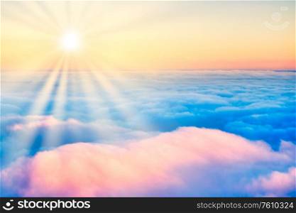 Sky and clouds at sunset with sun rays, aerial view from plane