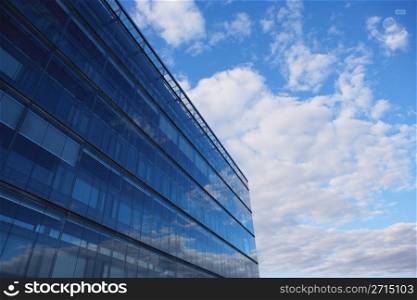 Sky and glass wall of an office building, reflections of clouds