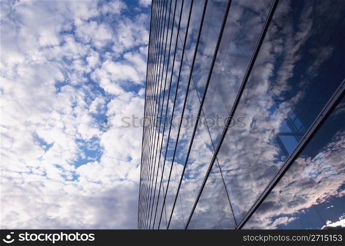Sky and glass wall of an office building, reflections of clouds.