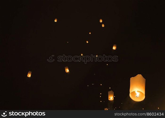 Sky lanterns glowing against black night sky, Pai, Thailand