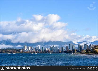 Skyline of condominiums in the West End of Vancouver, British Columbia, Canada, viewed from across bay with fog and clouds lifting.