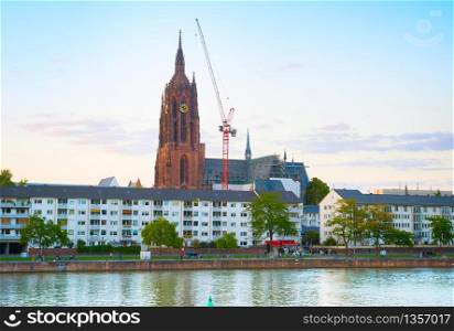 SKyline of Frankfurt with people walking by the Main river and construction of Frankfurt Cathedral in the background. Germany