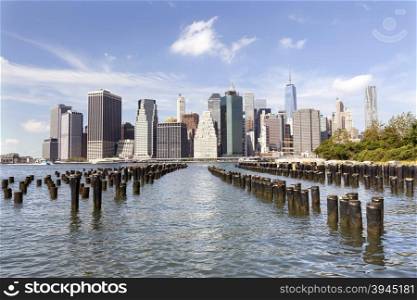skyline of lower manhattan over east river seen from brooklyn bridge park on sunny day