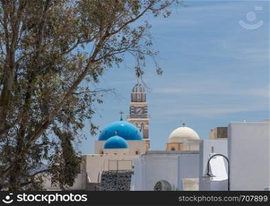 Skyline with clock tower and domes in village of Fira on Santorini. Clock tower and domes on Greek Orthodox church in Fira