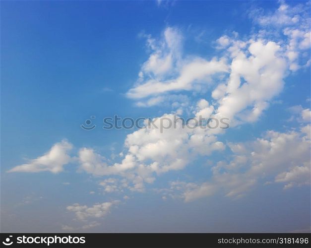Skyscape of blue sky and white fluffy clouds.