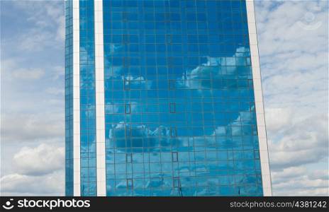 skyscraper mirror wall against cloudscape with reflection of the clouds