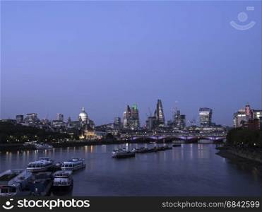 skyscrapers in london city with st paul's cathedral at night behind blackfriars bridge over thames river